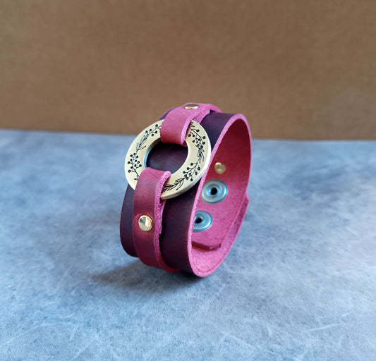 Red leather bracelet with gold brass O ring on a textured surface