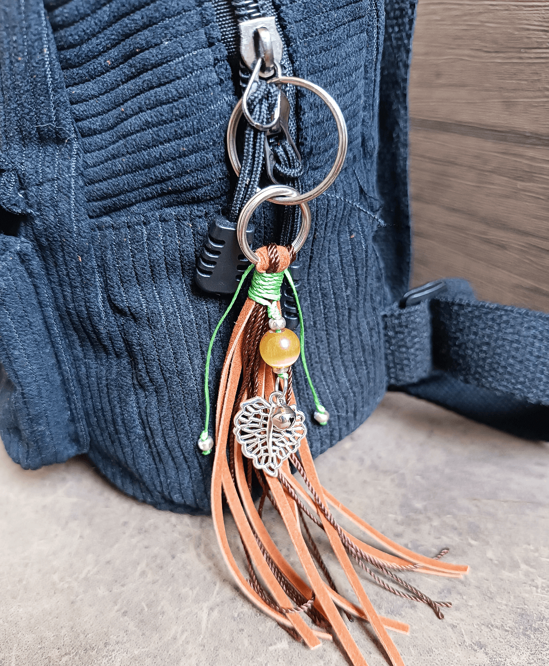 Keychain with tassels and beads attached to a blue textured bag.
