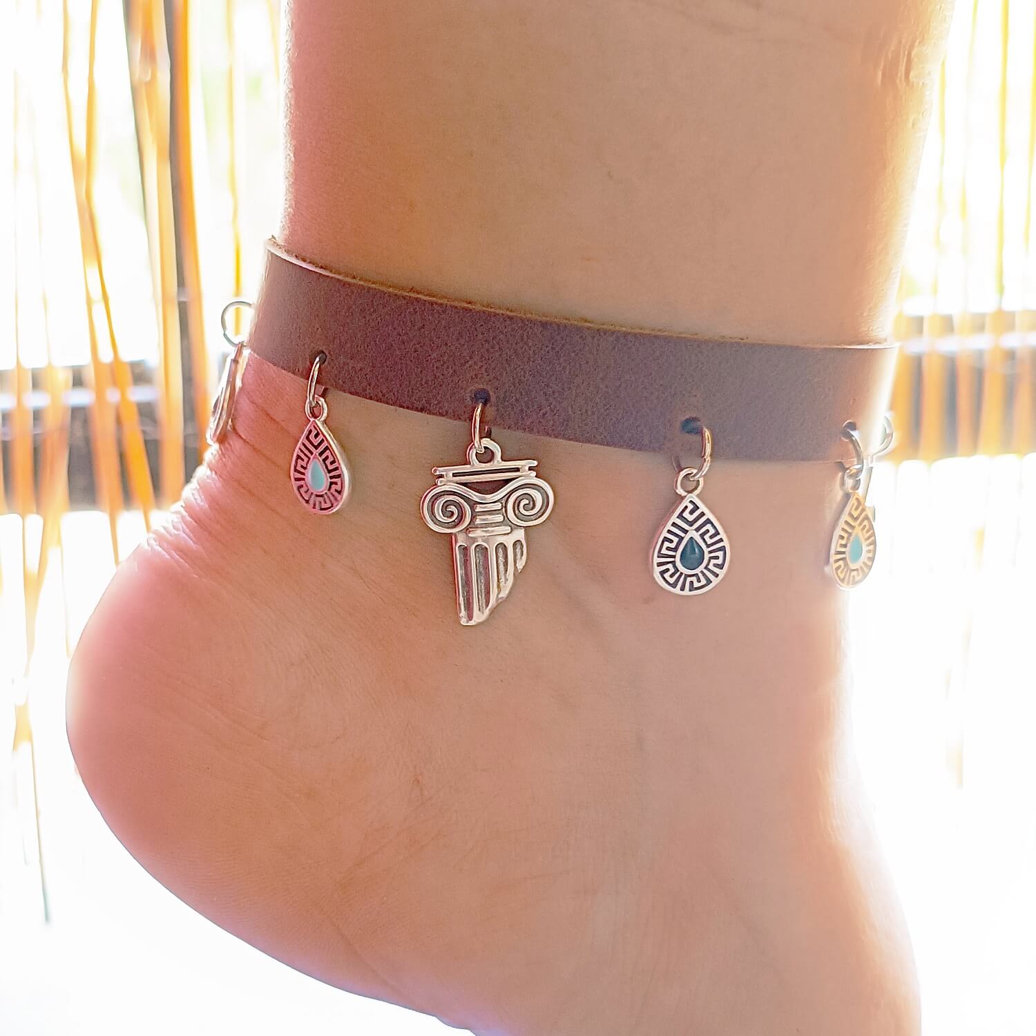Ankle bracelet with charms on a person's ankle against a blurred background