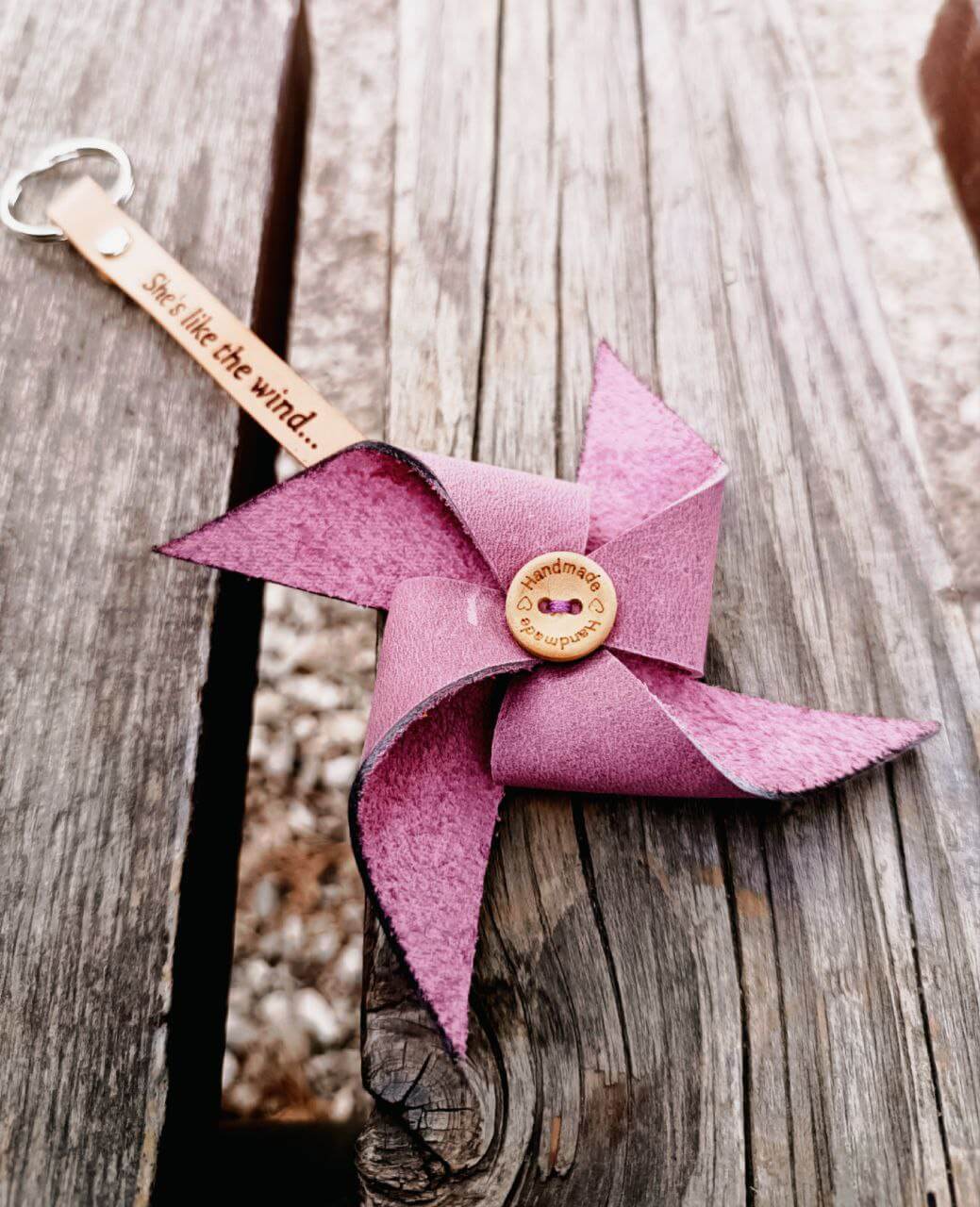 Pink pinwheel keychain with a button on a wooden surface