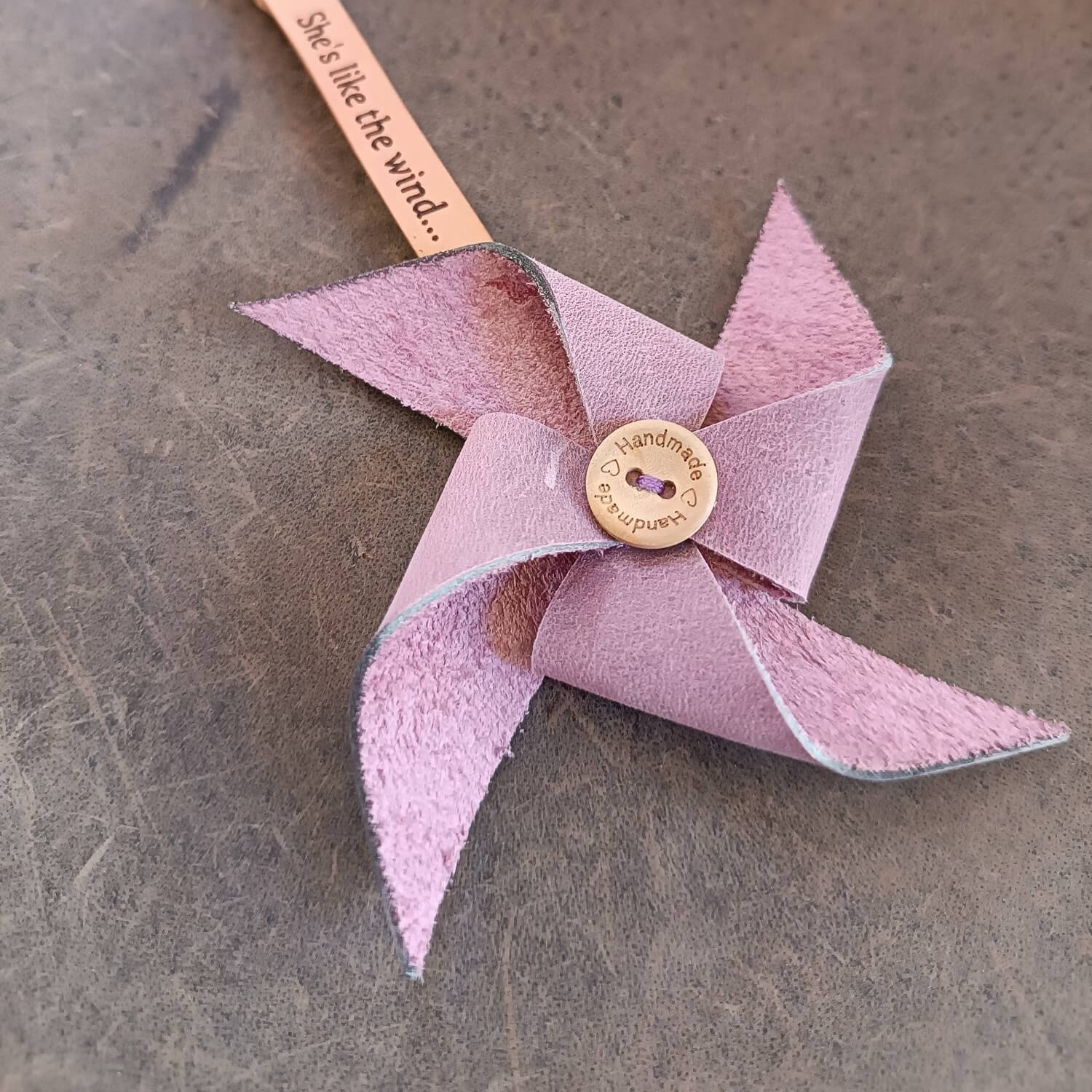 Pink pinwheel with a button in the center on a textured surface