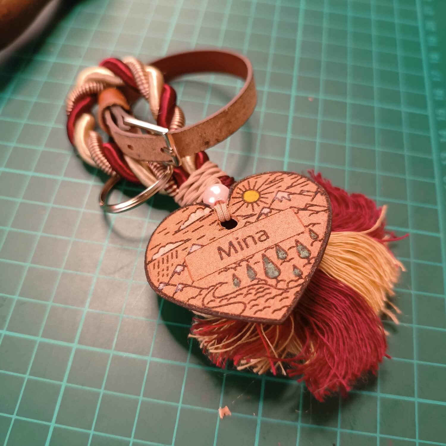 Heart-shaped keychain with 'Mina' engraving on a green grid background