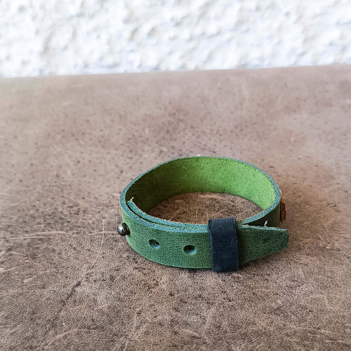 A green leather wrap bracelet in watchband style, backside view of closure