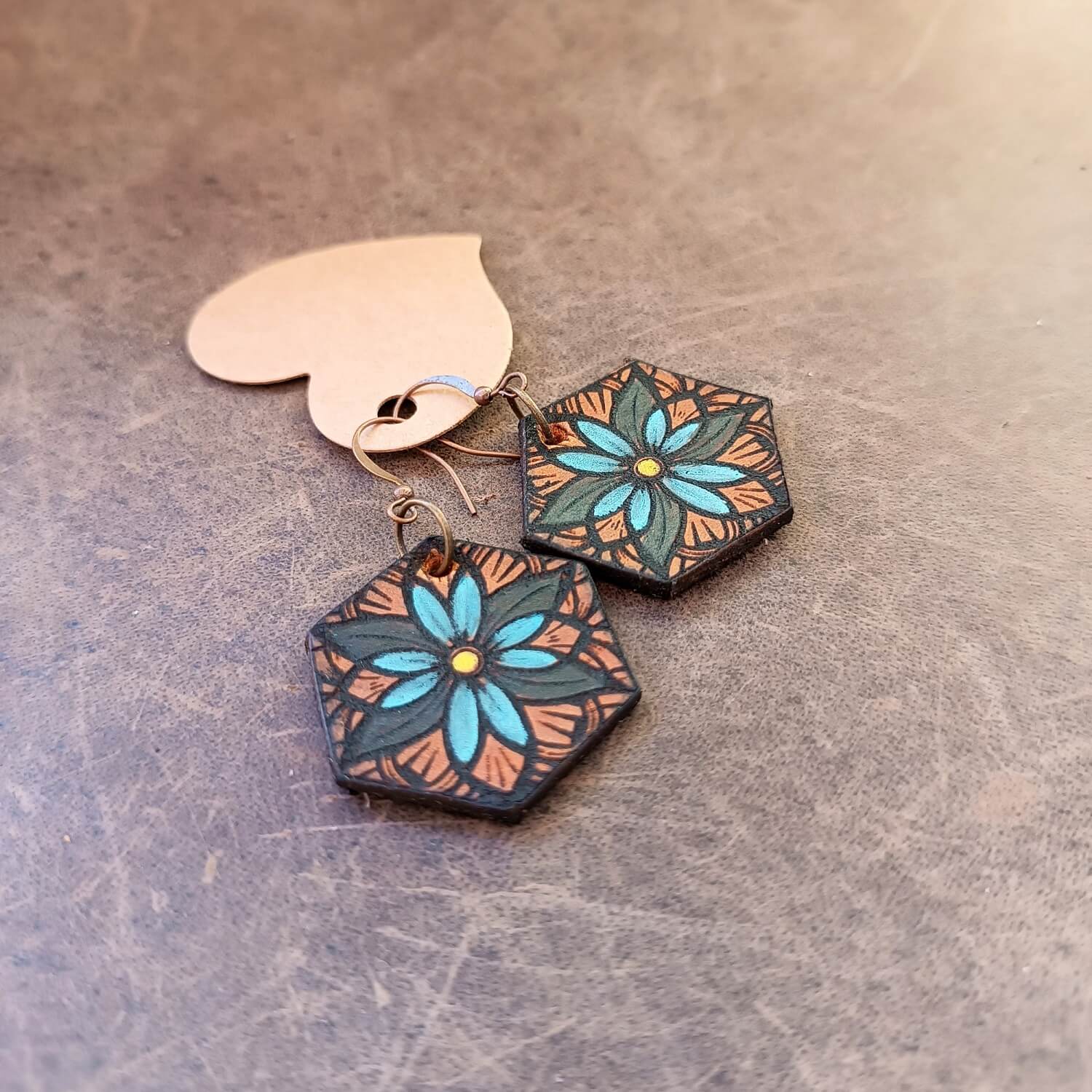 Hexagonal floral earrings on a textured surface