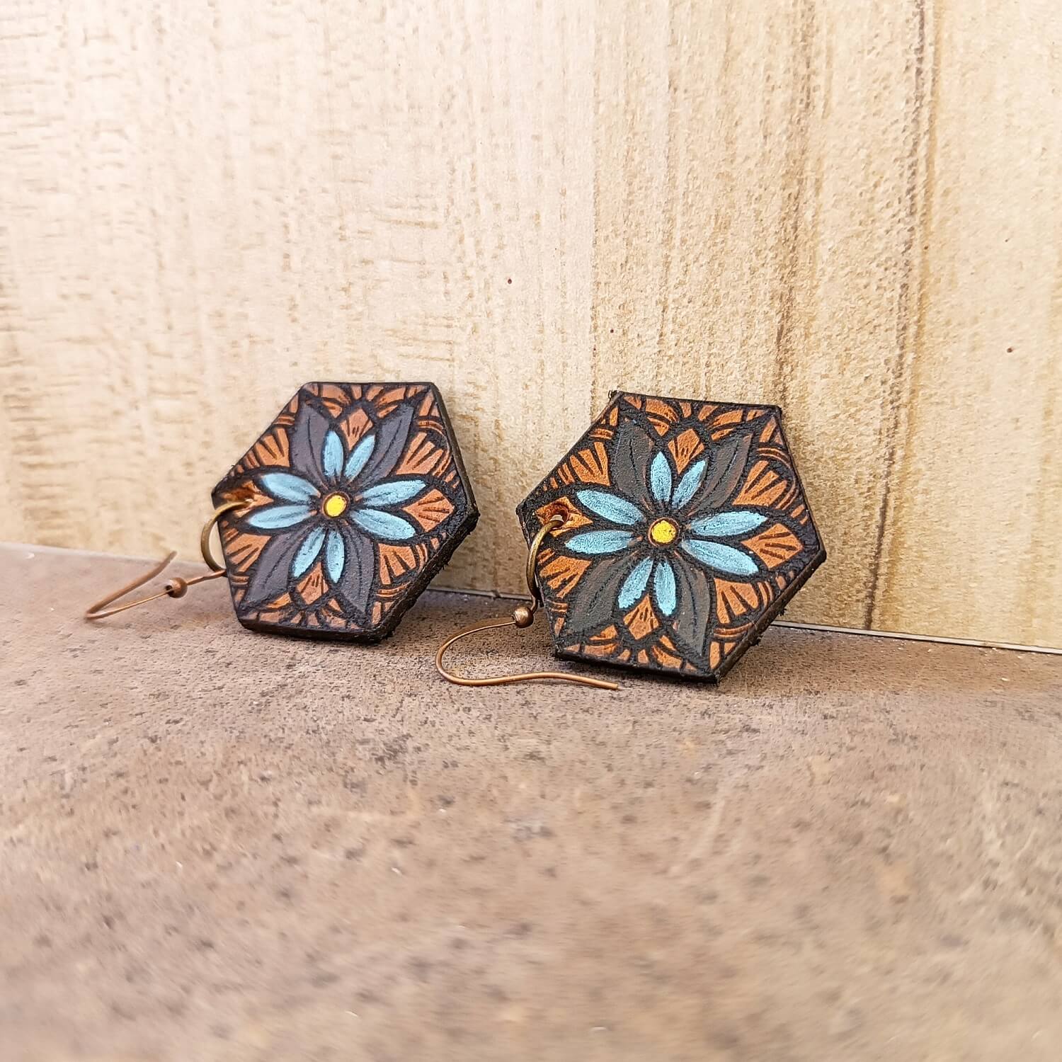 Hexagonal earrings with floral design on a wooden surface