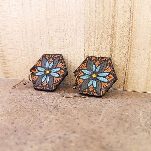 Hexagonal earrings with floral design on a wooden surface
