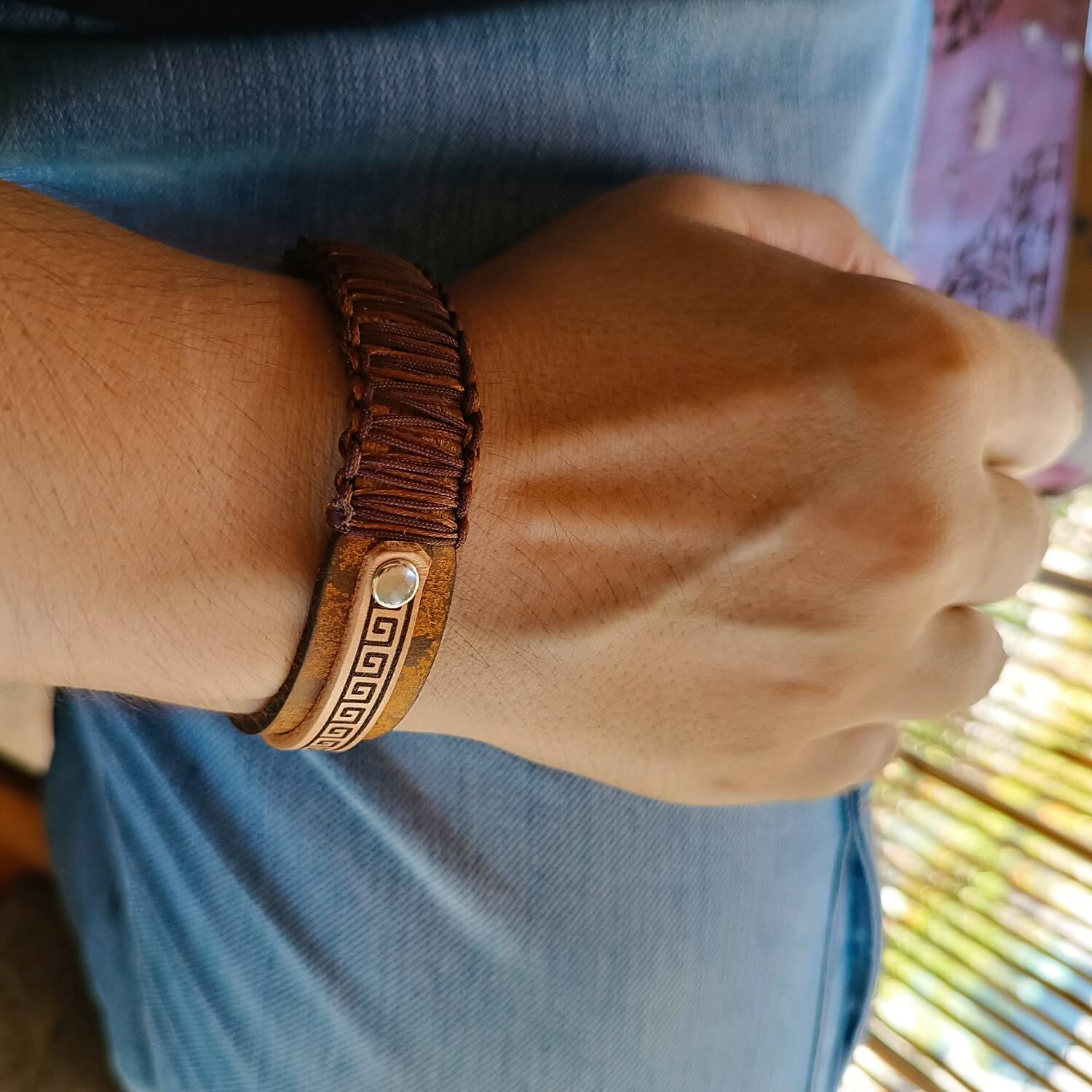 Close-up of a wrist wearing a brown leather bracelet with a decorative metal clasp.