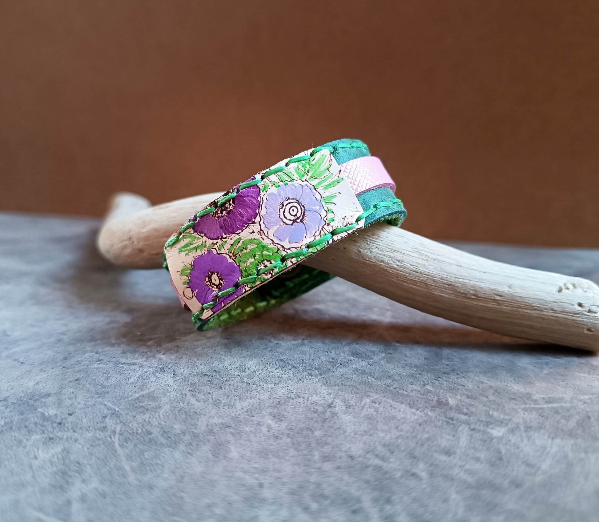 Floral-patterned bracelet on a wooden stick with a neutral background