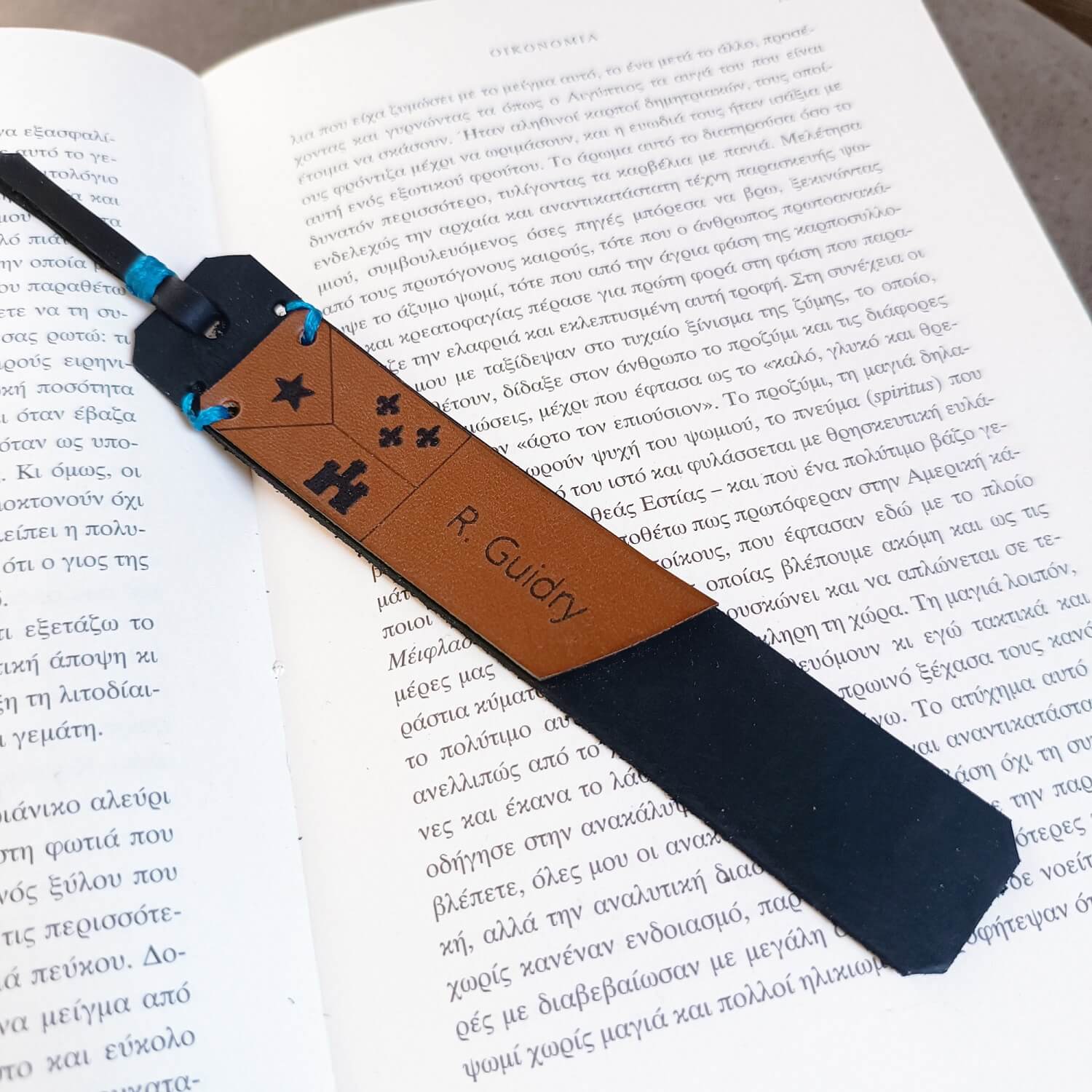 A personalized Cajun leather bookmark with an Acadian flag, placed on an open book.