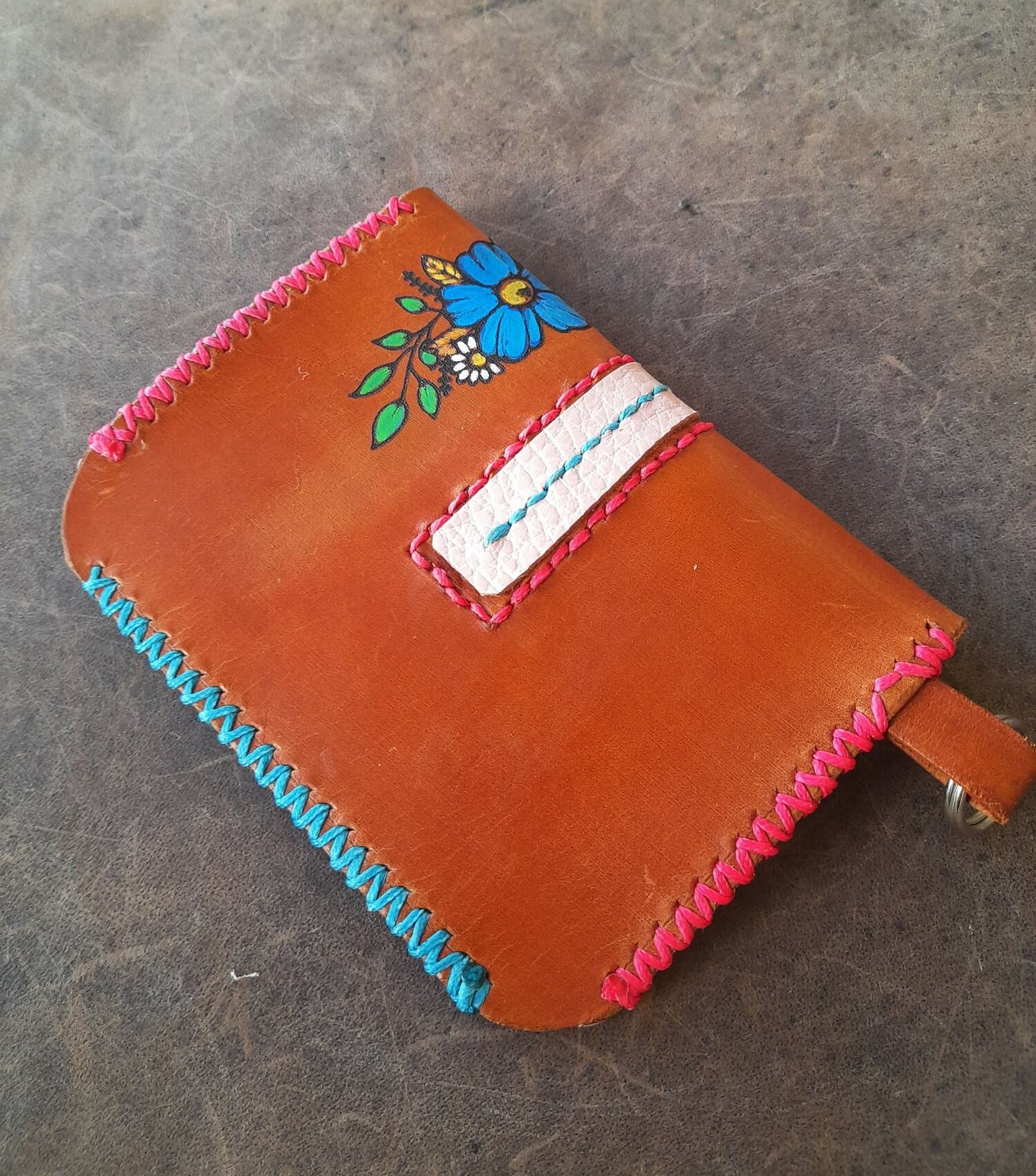 Brown leather wallet with floral embroidery on a gray surface, backside view