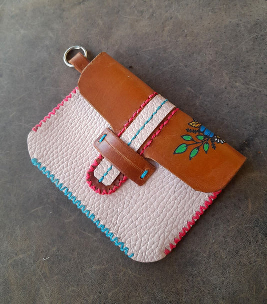 Small leather pouch with floral embroidery on a gray surface