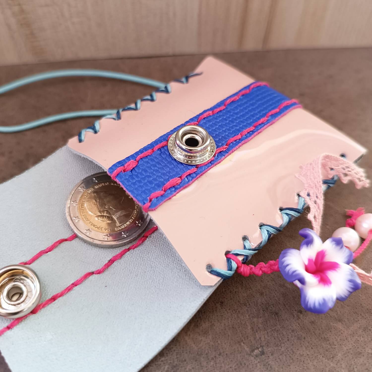 Handmade coin purse with colorful stitching and decorative elements on a wooden surface.