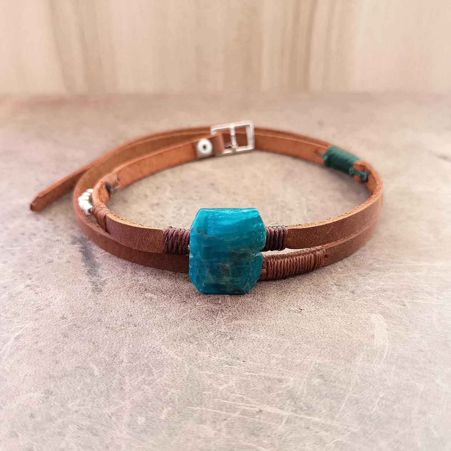 Brown leather choker with a blue stone on a textured surface