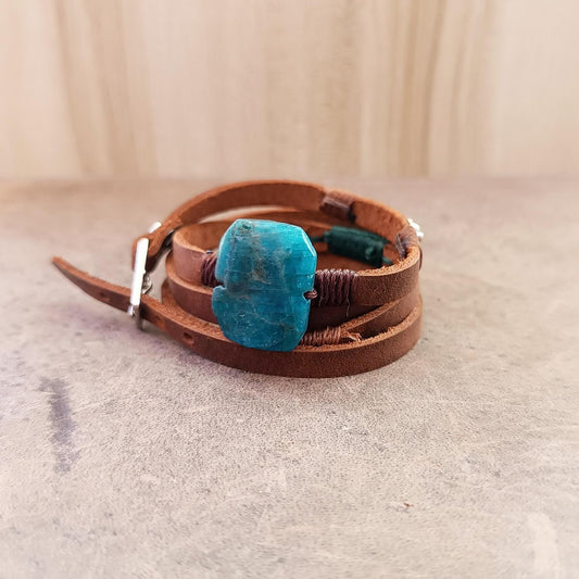 Brown leather bracelet with a blue stone on a light gray surface