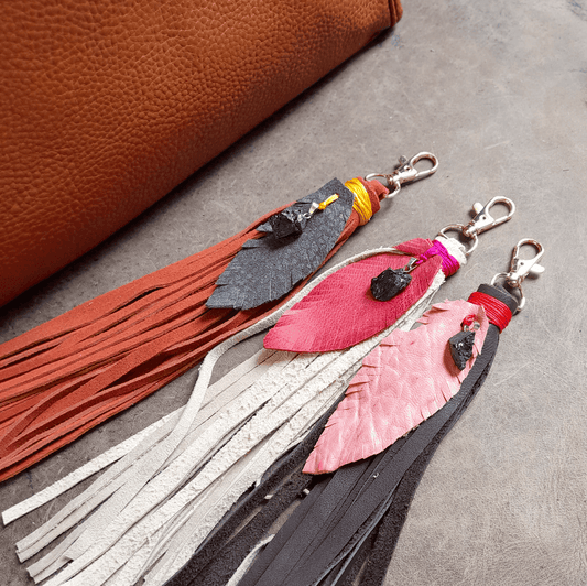 Leather tassel keychains with colorful accents on a gray surface