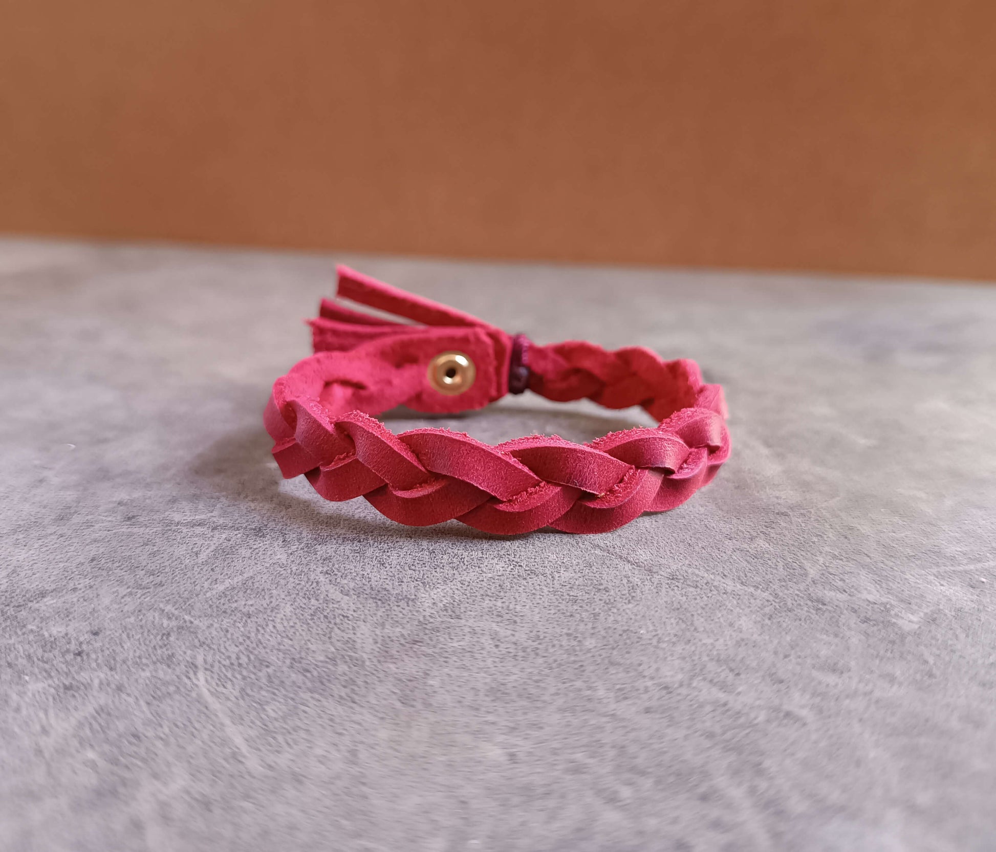 Red braided bracelet on a gray surface with a beige background