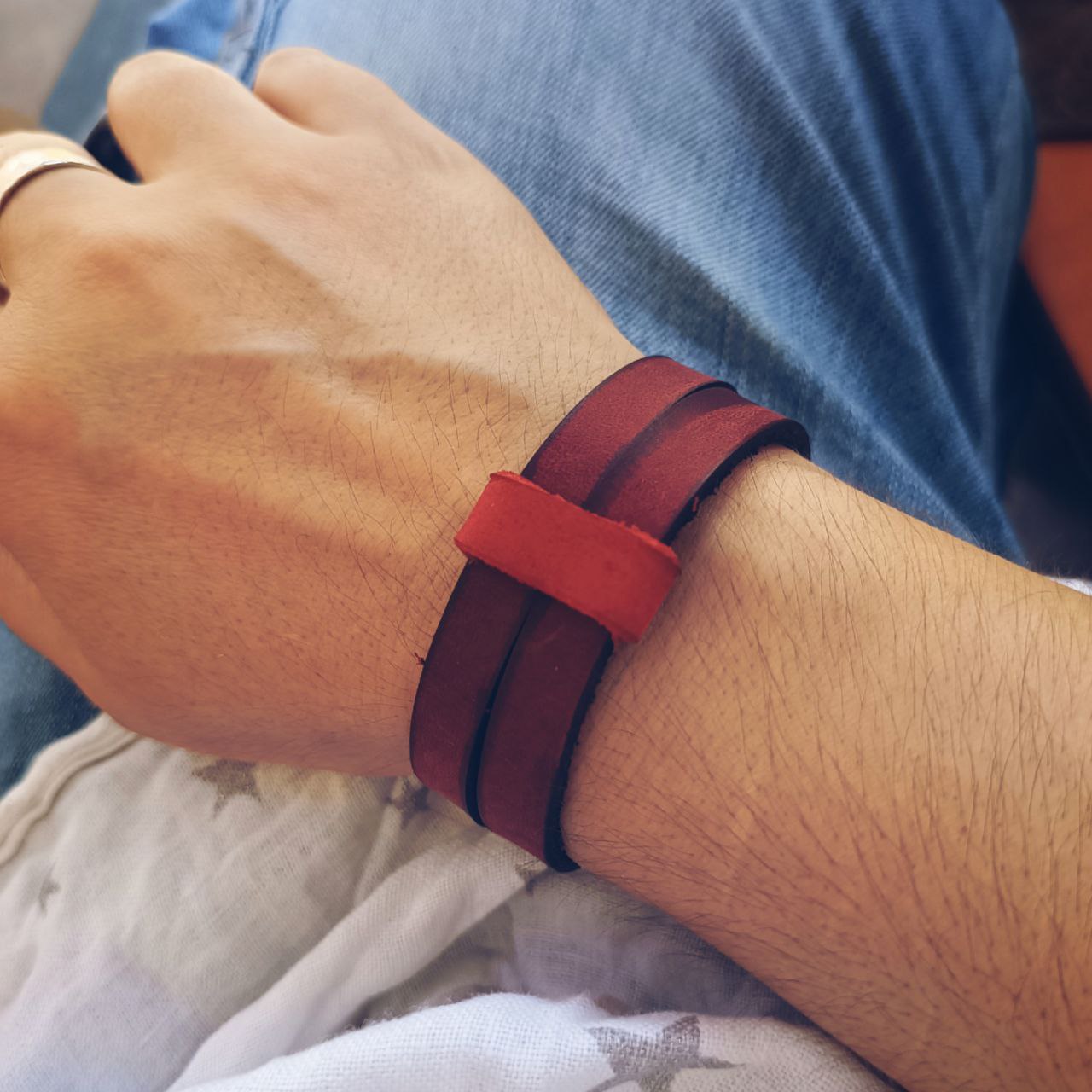 Red leather choker cuff worn on wrist, with the closure loop as centerpiece