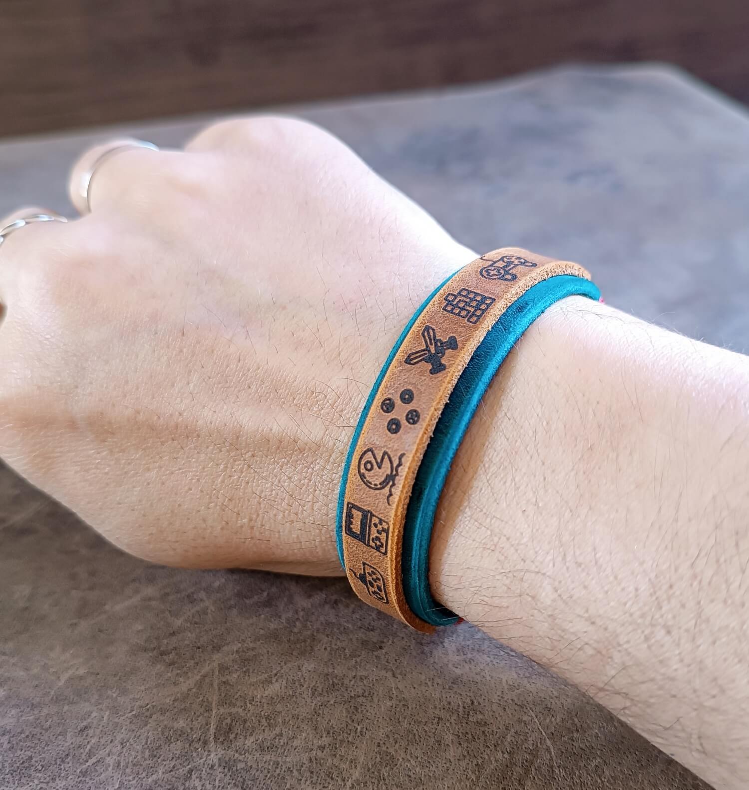 Bracelet with engraved symbols on a wrist against a neutral background