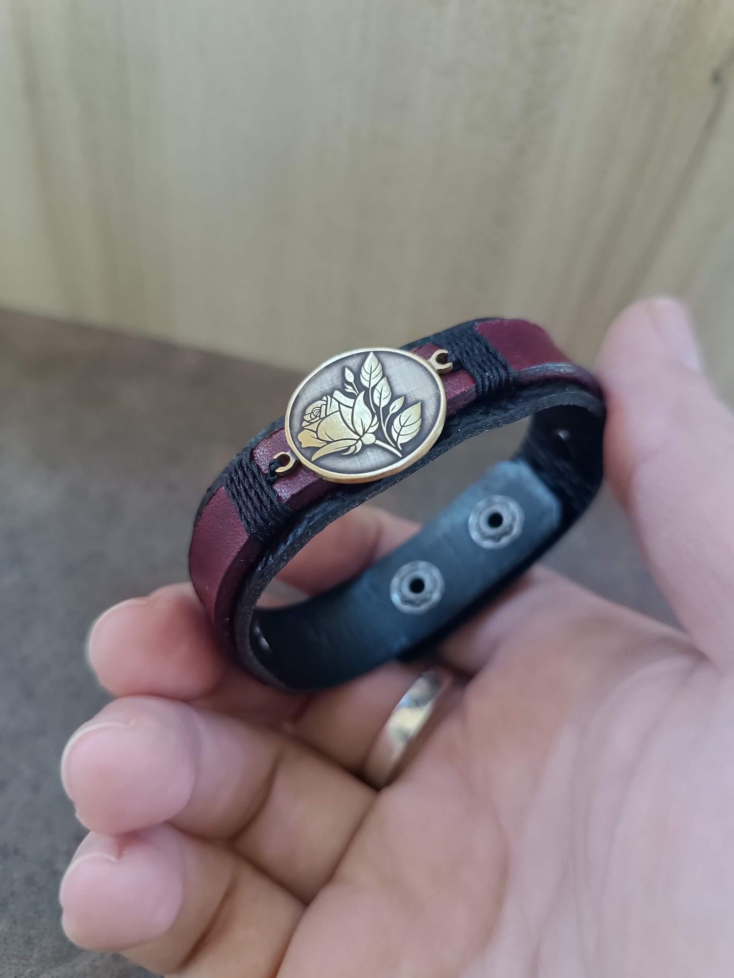 Bracelet with a rose pendant held in a hand against a neutral background