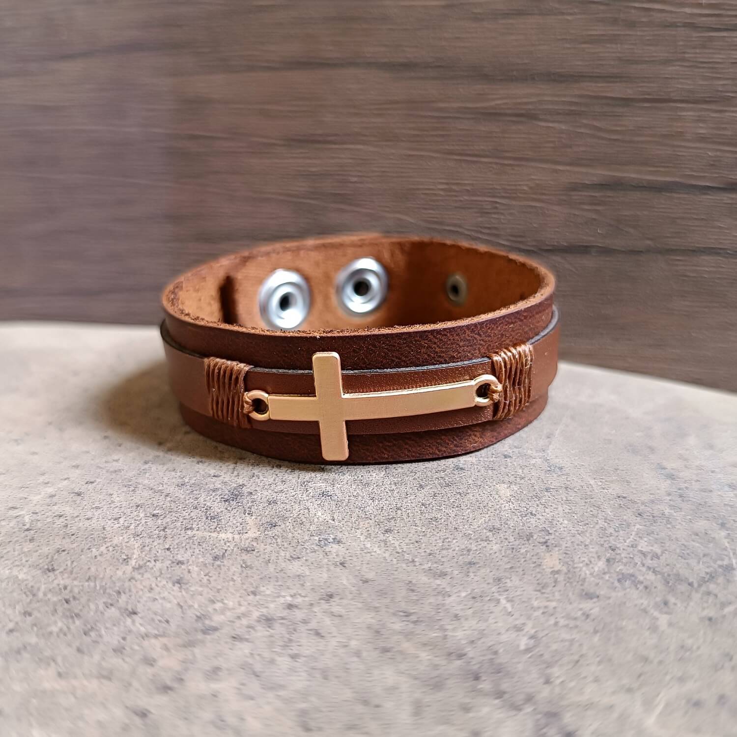 Rose Gold Cross Leather Cuff on dark brown leather, front view close up