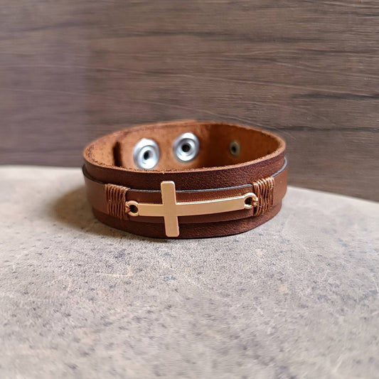 Rose Gold Cross Leather Cuff on dark brown leather, front view close up