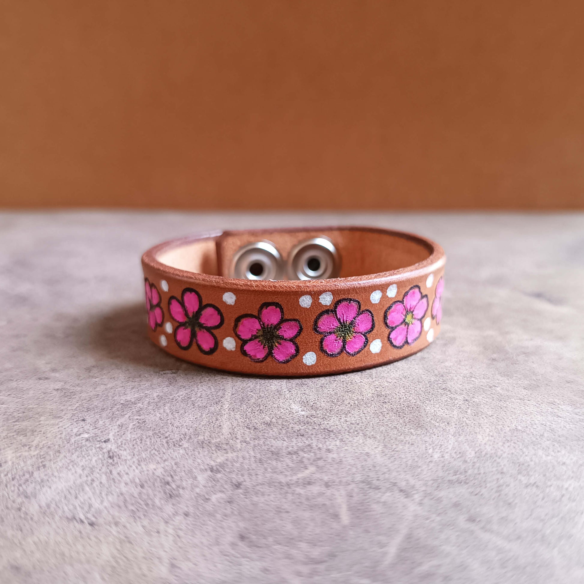 Leather bracelet with pink floral patterns on a neutral background