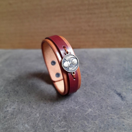 Side angle showing layered leather detail and symbolic scarab centerpiece.