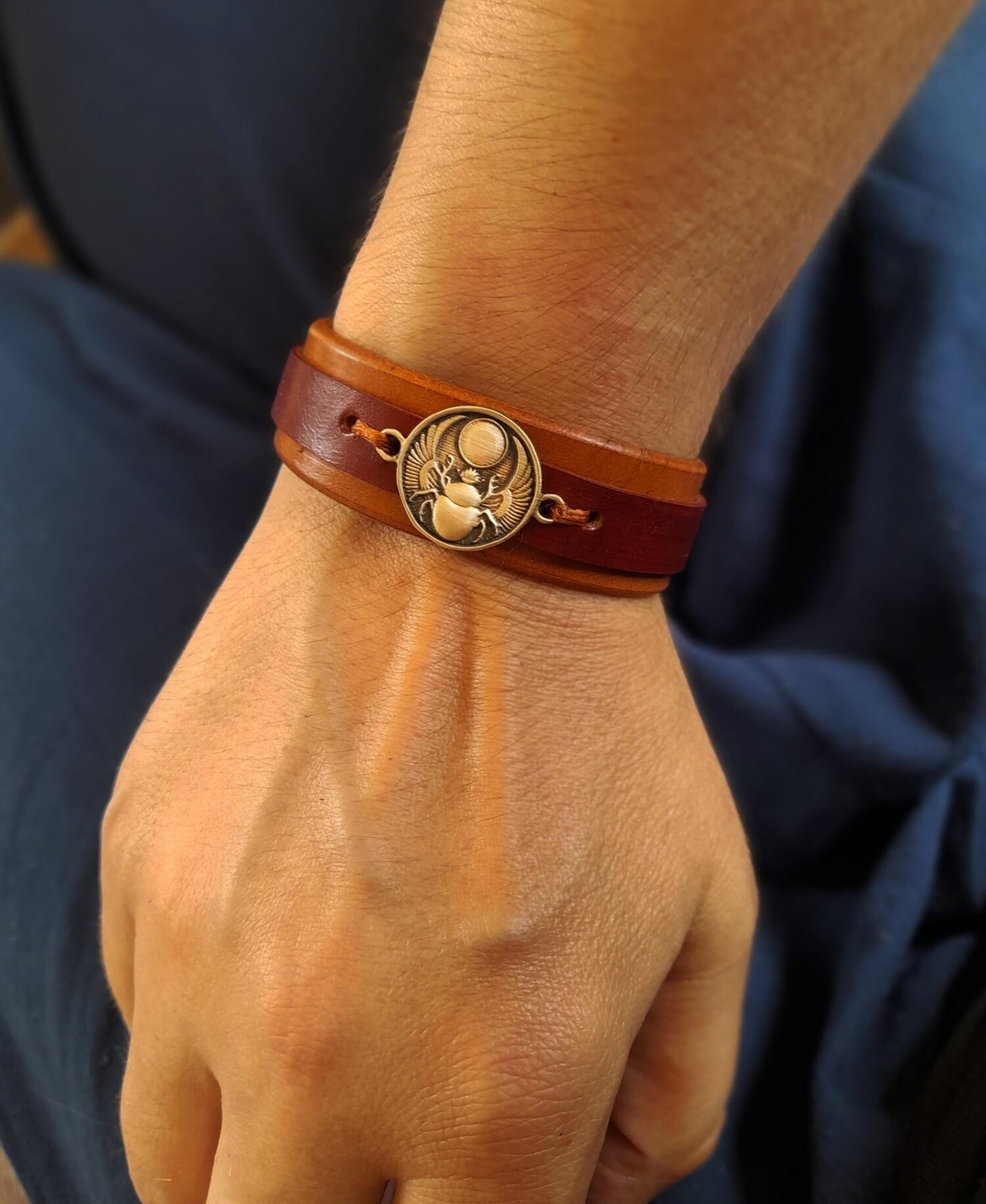 Scarab leather cuff worn on wrist, styled with earthy and natural tones.