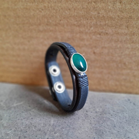 side view of The OOAK Dark Green Aventurine Leather Bracelet: A layered chestnut brown and black full-grain leather bracelet featuring a rare natural dark green aventurine stone on a sterling silver pendant, wrapped with black cord.