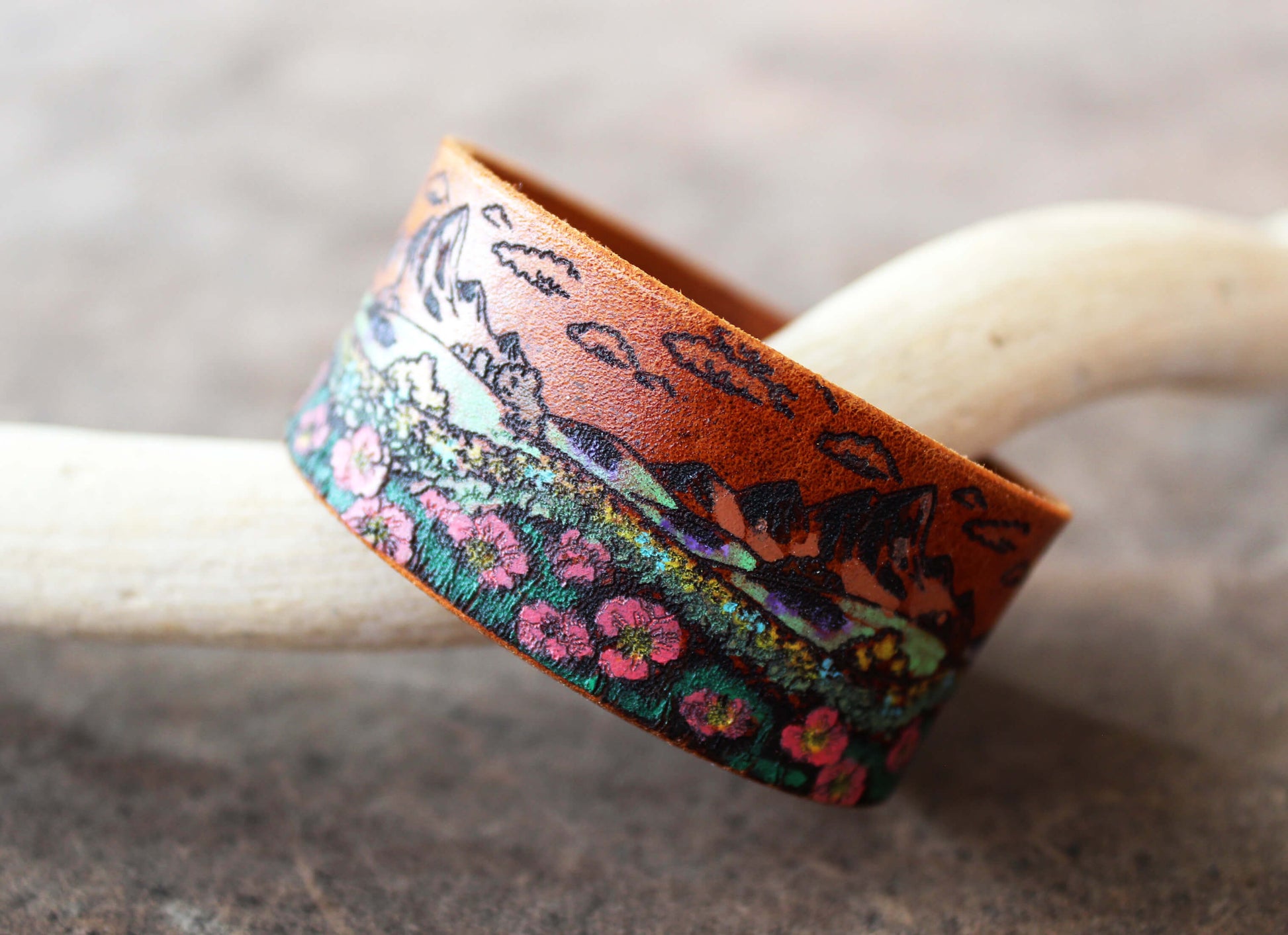 Leather cuff with floral and nature design on a neutral background