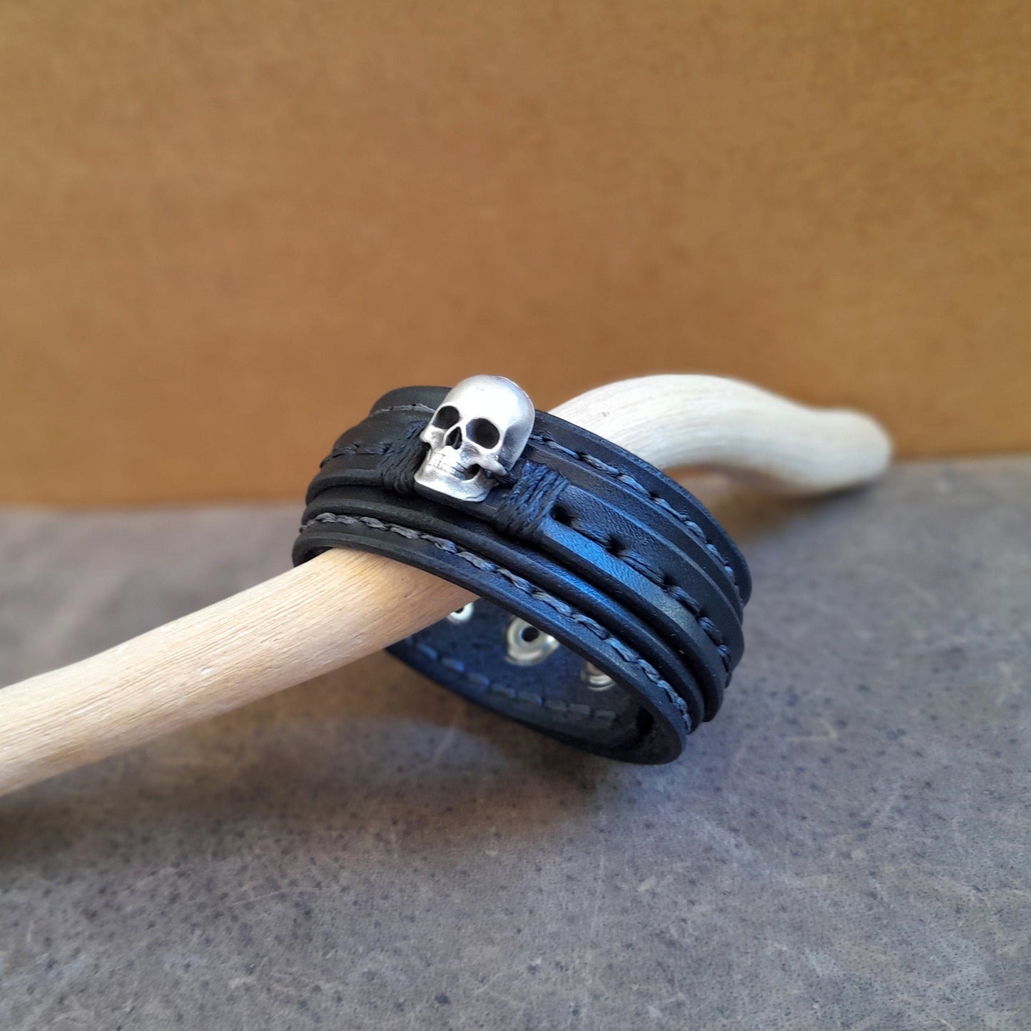 Detail of the hand-stitching on the layered black leather and the bold features of the solid silver skull.