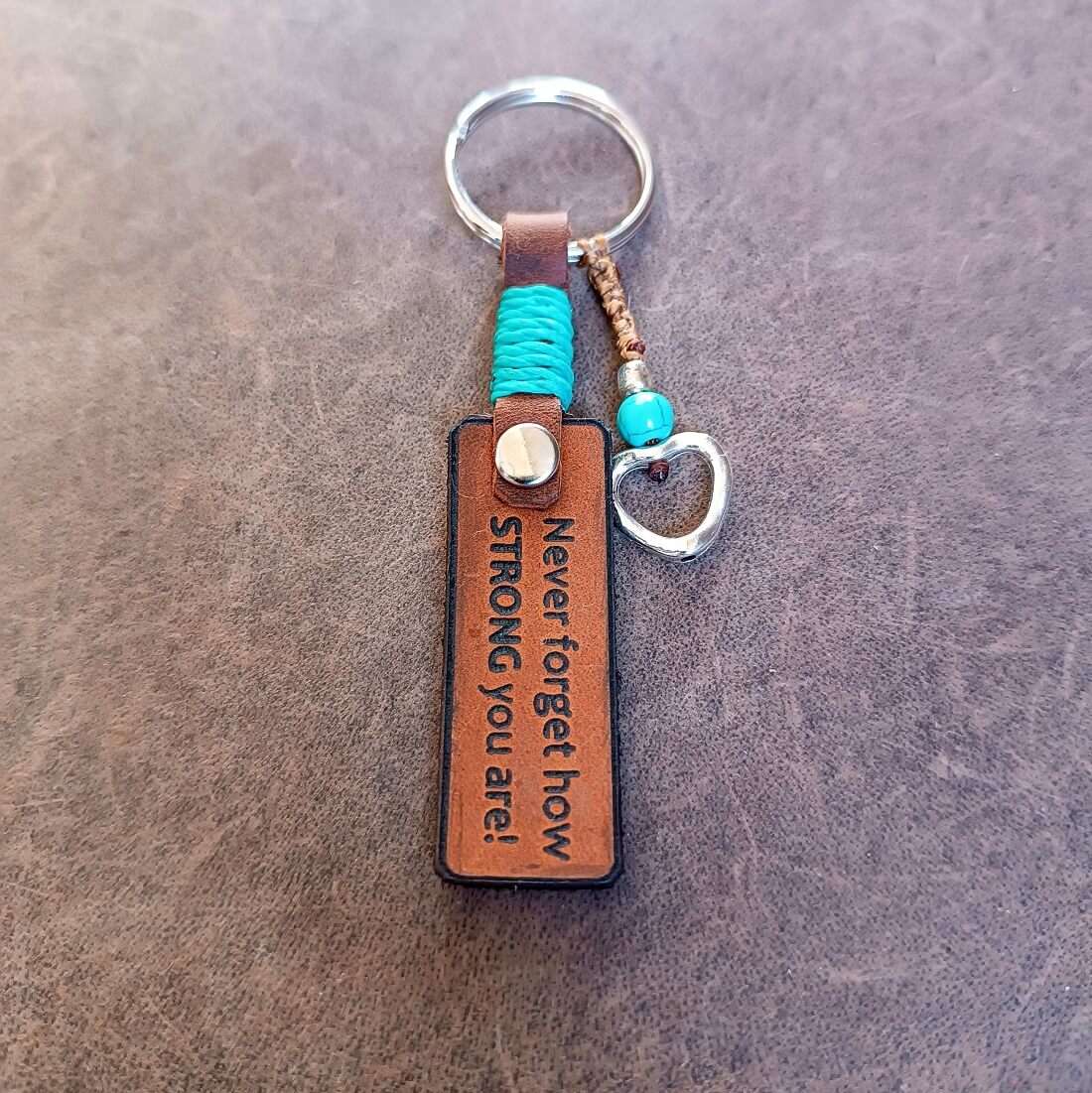 Leather keychain with motivational quote on a textured surface