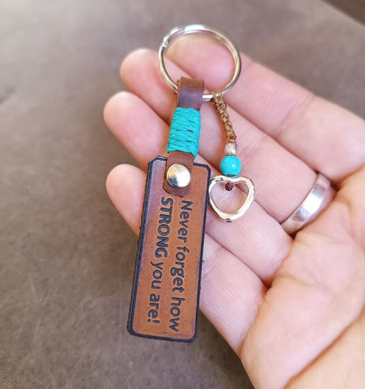 Keychain with motivational quote held by a hand on a neutral background