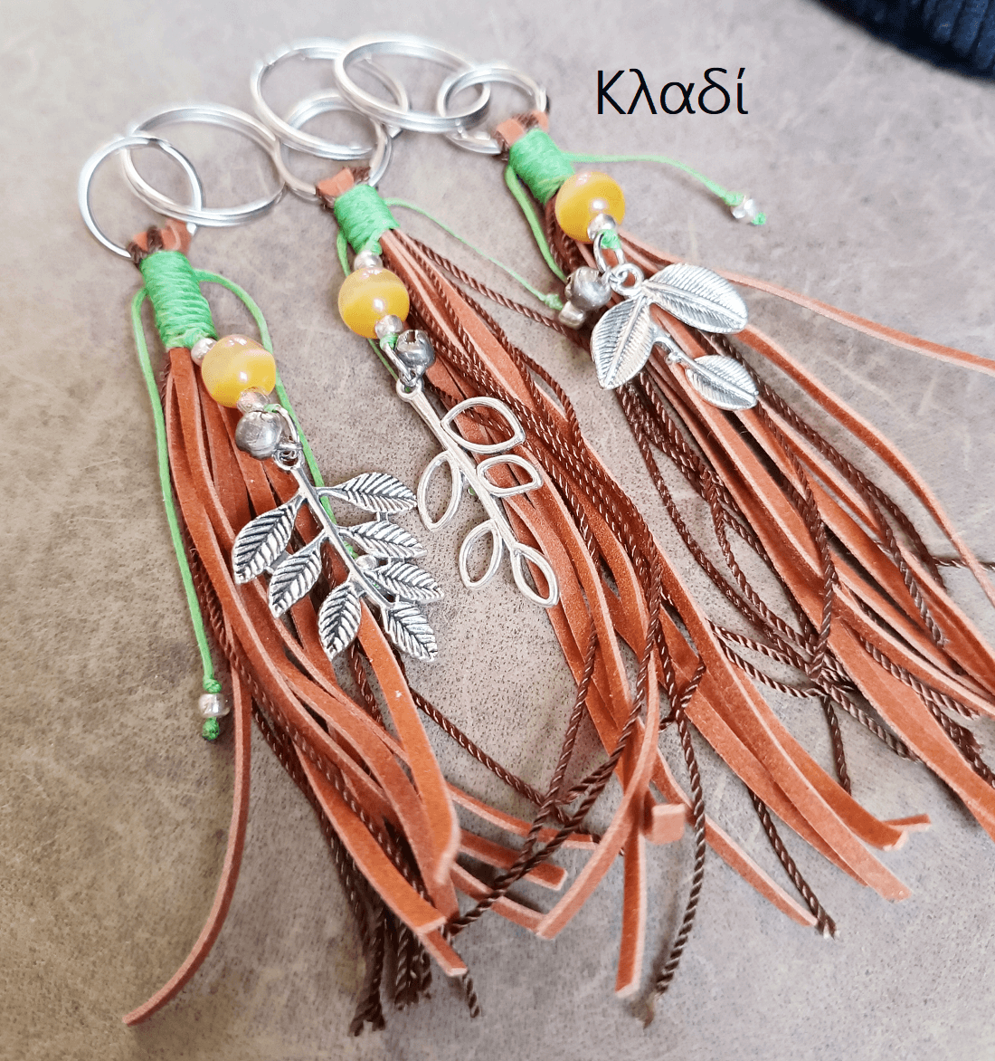 Decorative keychain with tassels and branch charms on a textured surface
