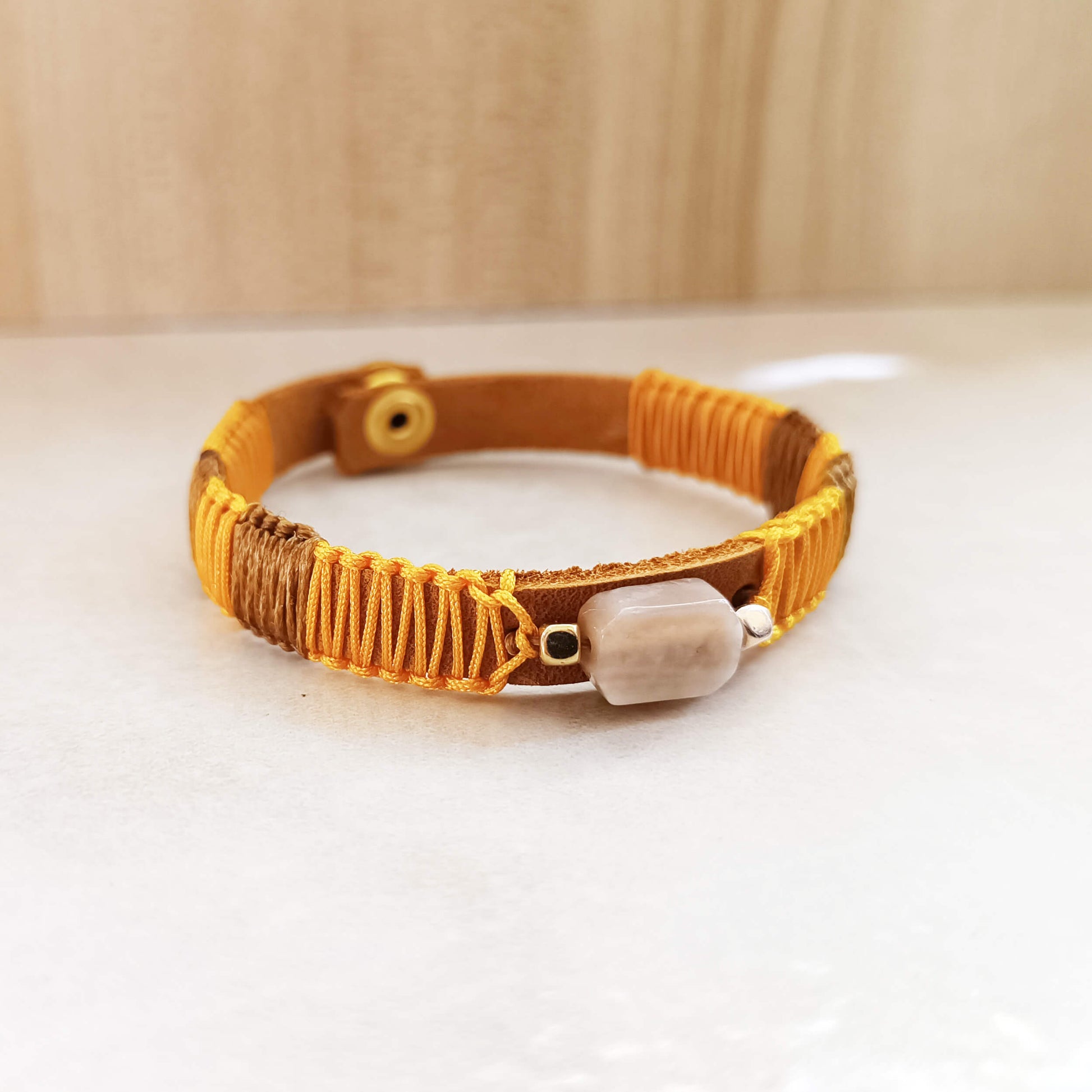 Bracelet with yellow and brown cord with Sunstone on a white surface