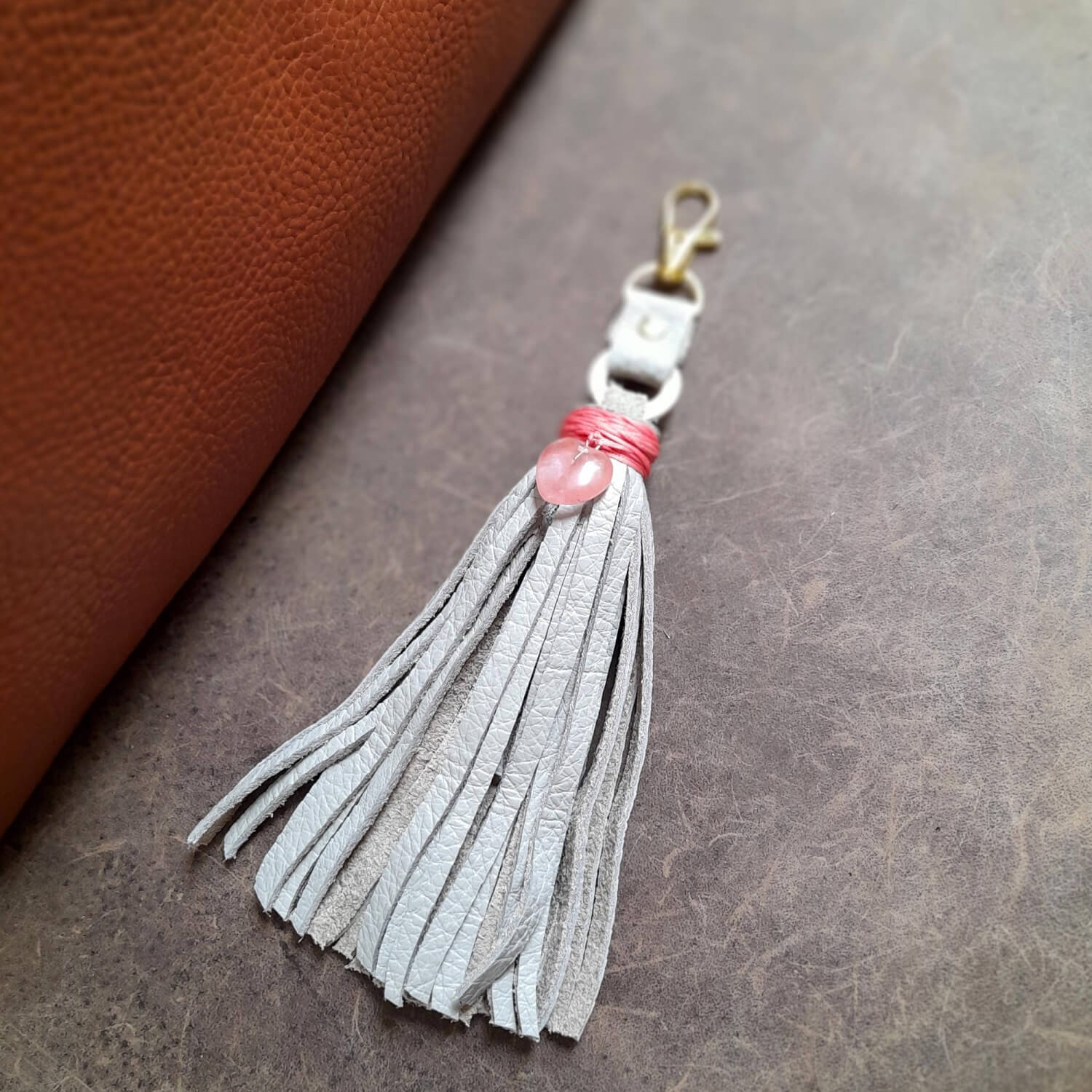 OOAK Rose Quartz Heart Charm with a gray leather tassel. Features a genuine Rose Quartz heart pendant wrapped with bright pink thread. Comes with a brass gold-tone O-ring and lobster clasp.
