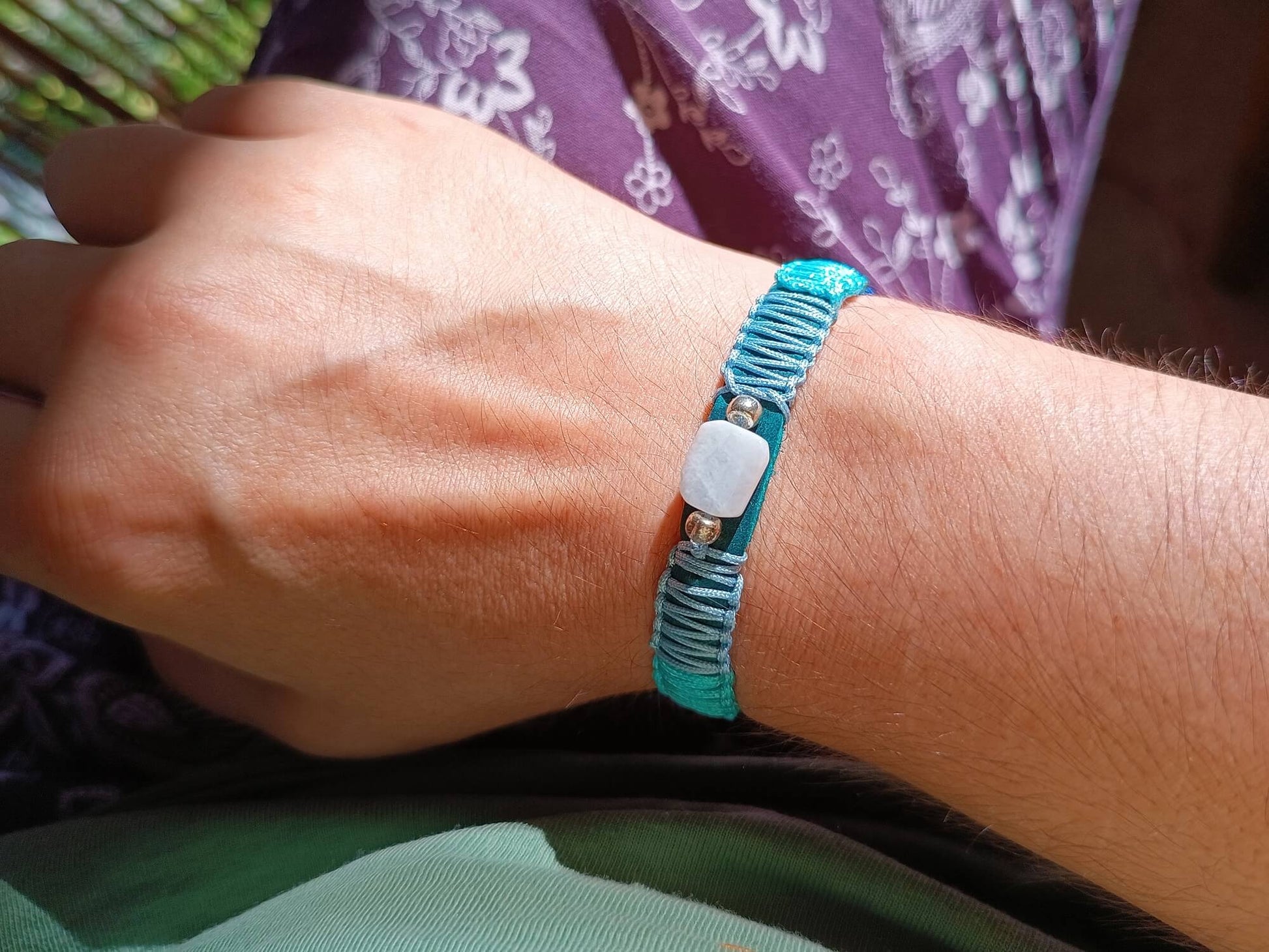 Close-up of a woman's wrist wearing a blue bracelet with moonstone