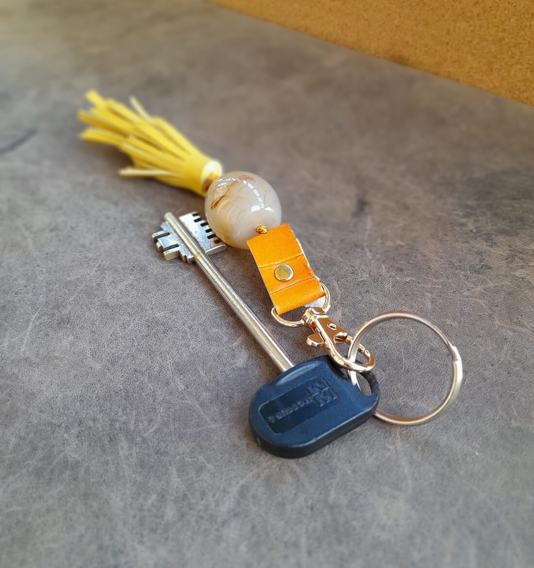 the yellow tassel Keychain with large yellow stone and decorative elements on a textured surface