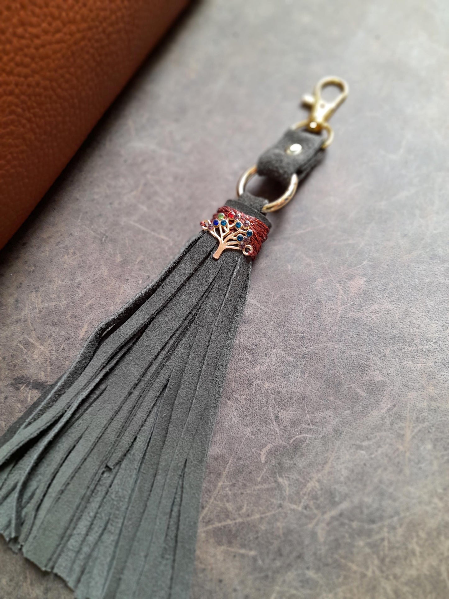 Close-up of the burgundy beeswax thread stitching on the green suede tassel head.