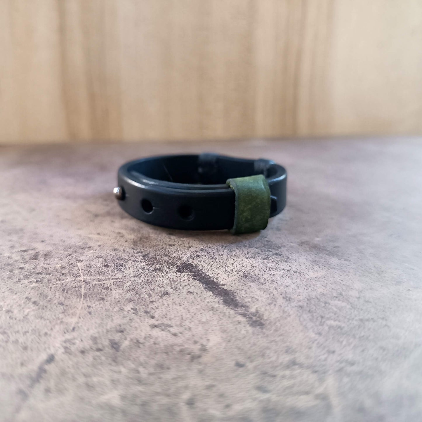 Black and green bracelet on a textured surface with a wooden background