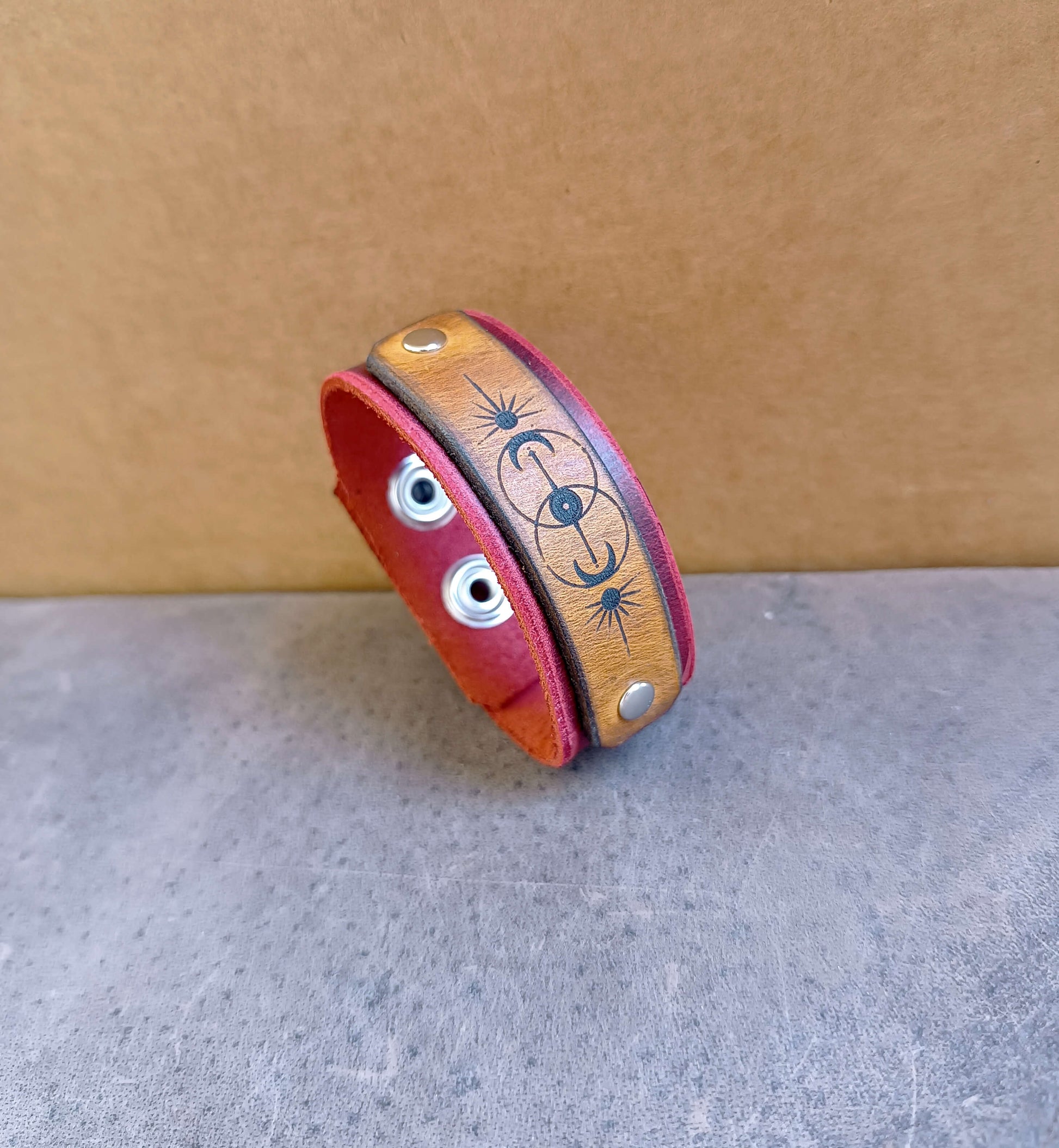 Leather bracelet with vesica piscis engraving on a gray surface