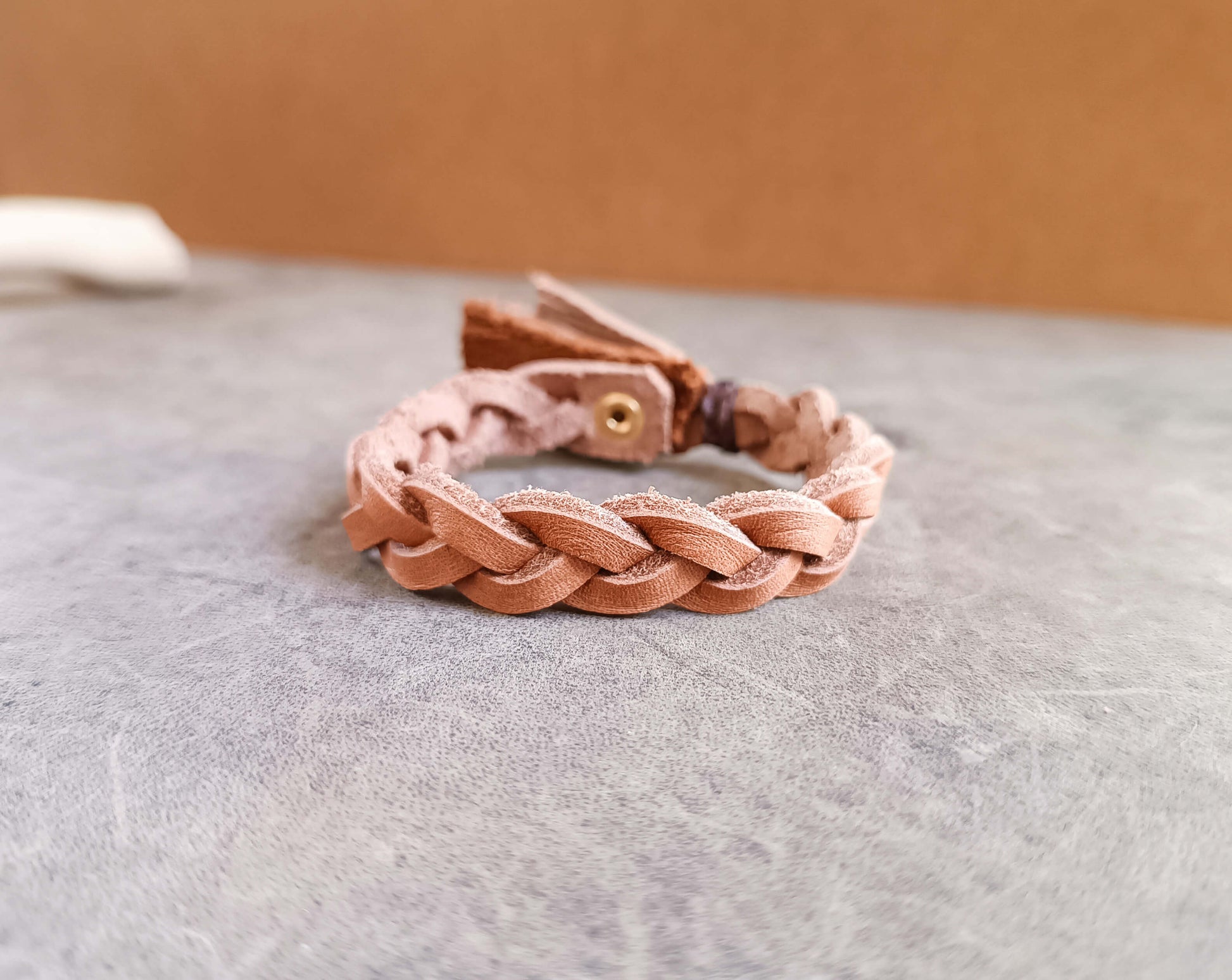 Warm Brown Braided leather bracelet on a textured surface with a neutral background