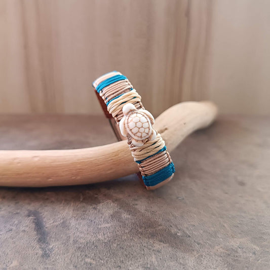 Bracelet with turtle charm on a wooden stick against a neutral background