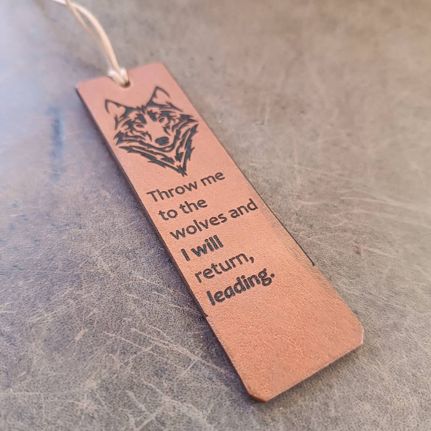Leather bookmark with wolf design and engraved text on a textured surface