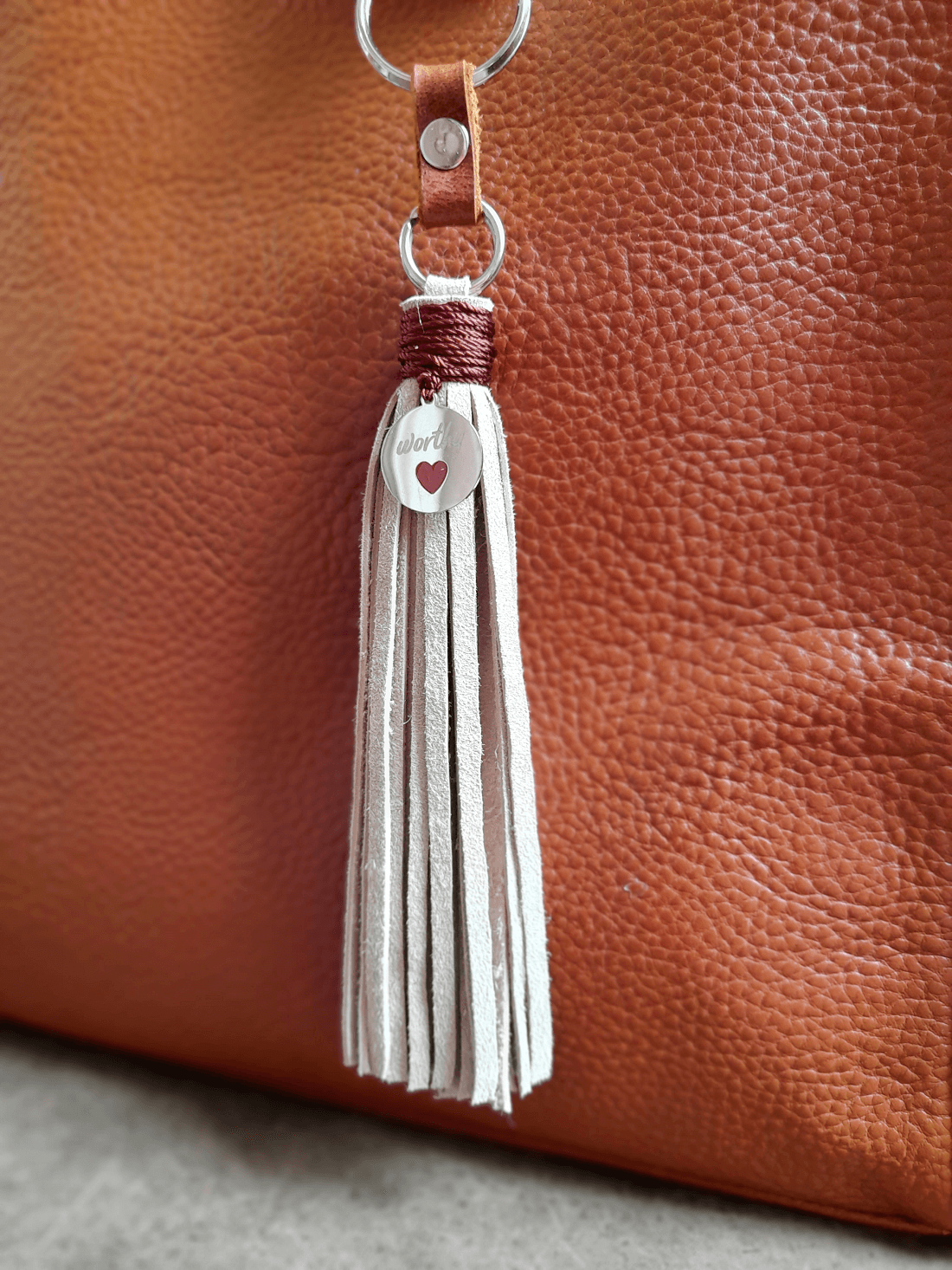 Tassel keychain with leather strap on a brown leather surface