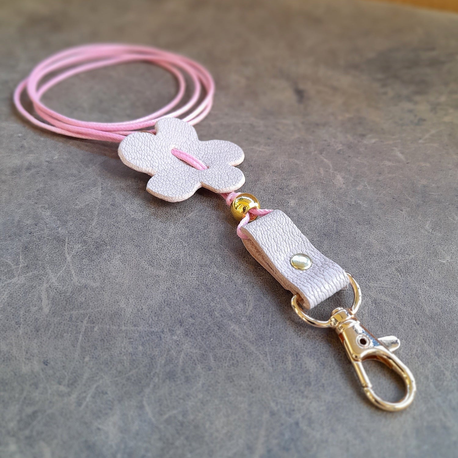 a sof pink lanyard with pink flower and gold lobster clasp to carry your phone
