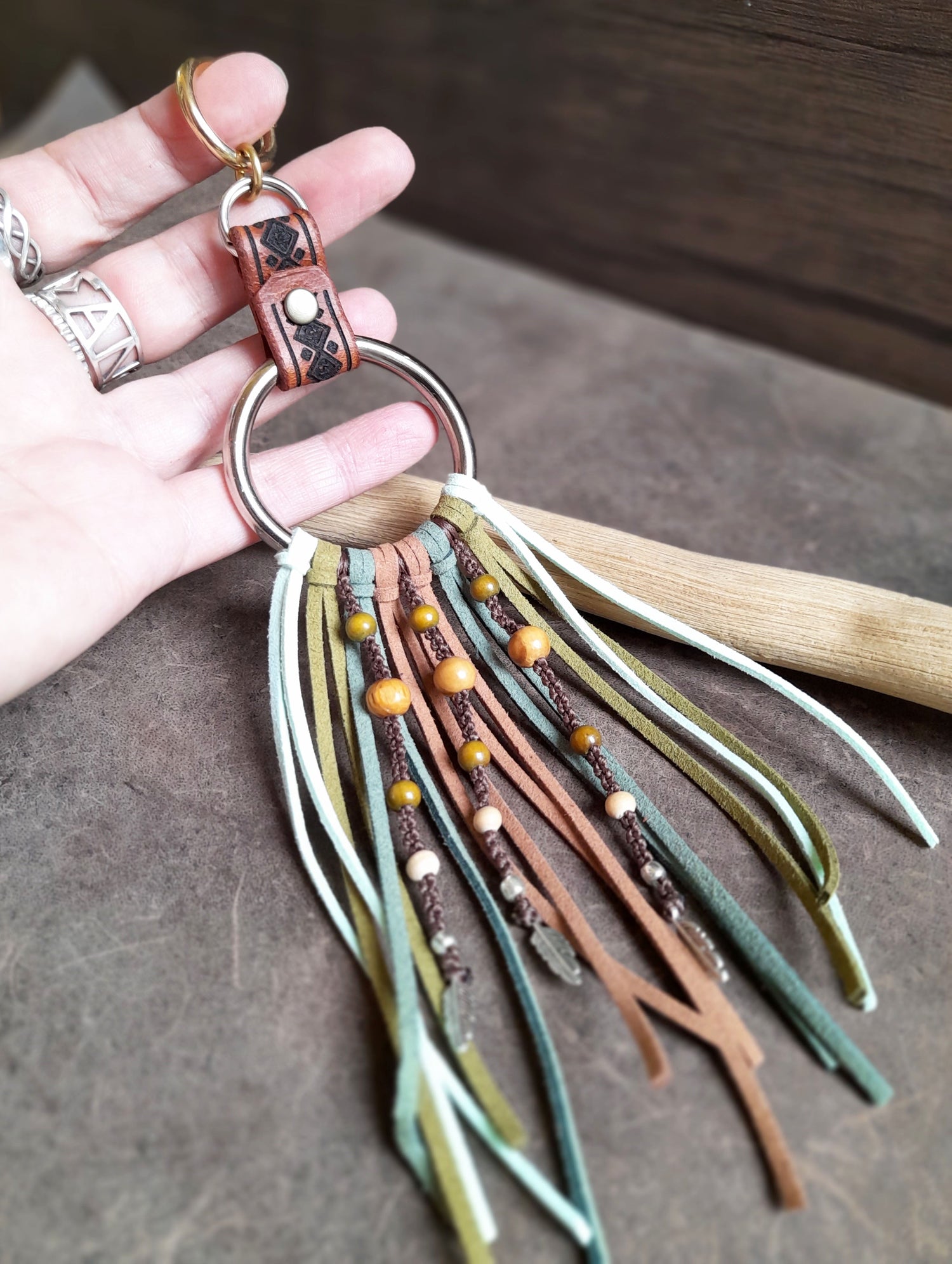 A one of a kind fringe bag charm with large brass O ring and suede cords with wooden beads