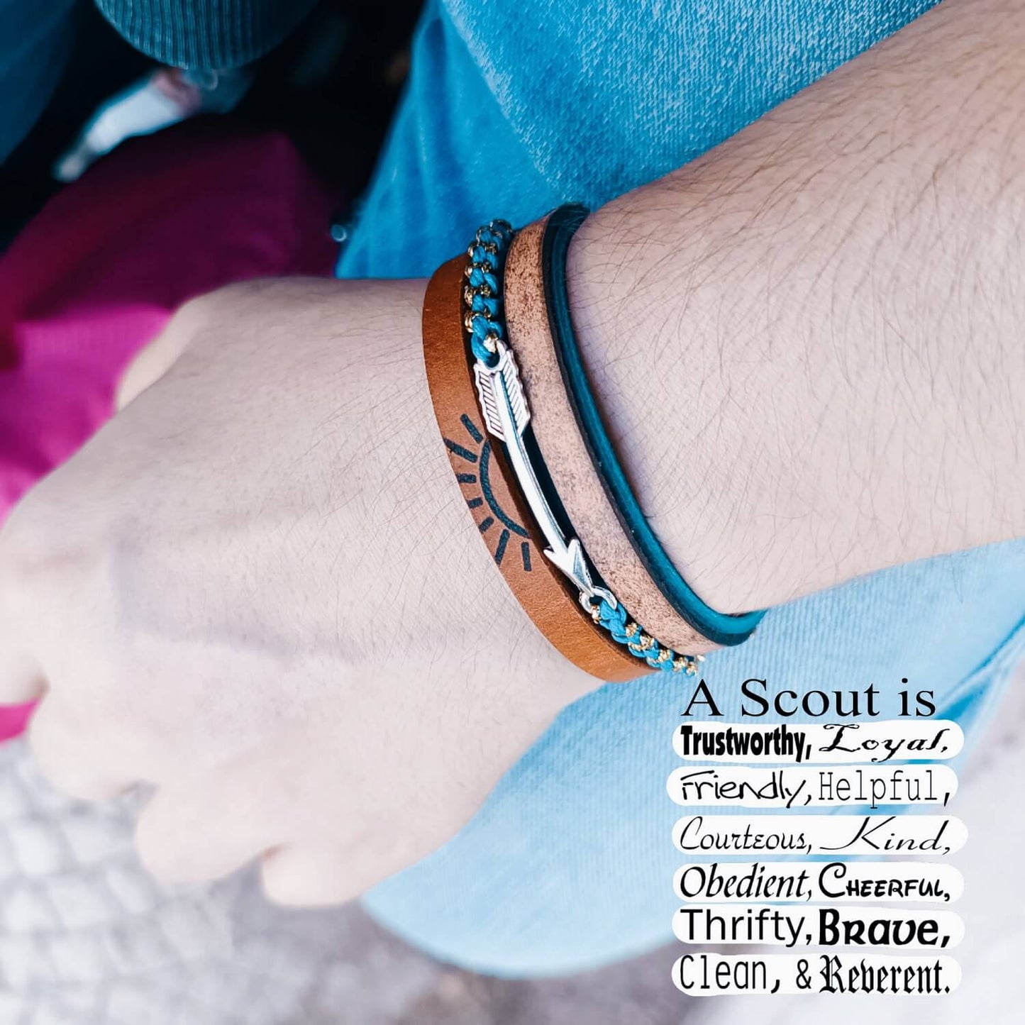 Close-up of a wrist wearing a bracelet with a Scout values quote on a blurred background