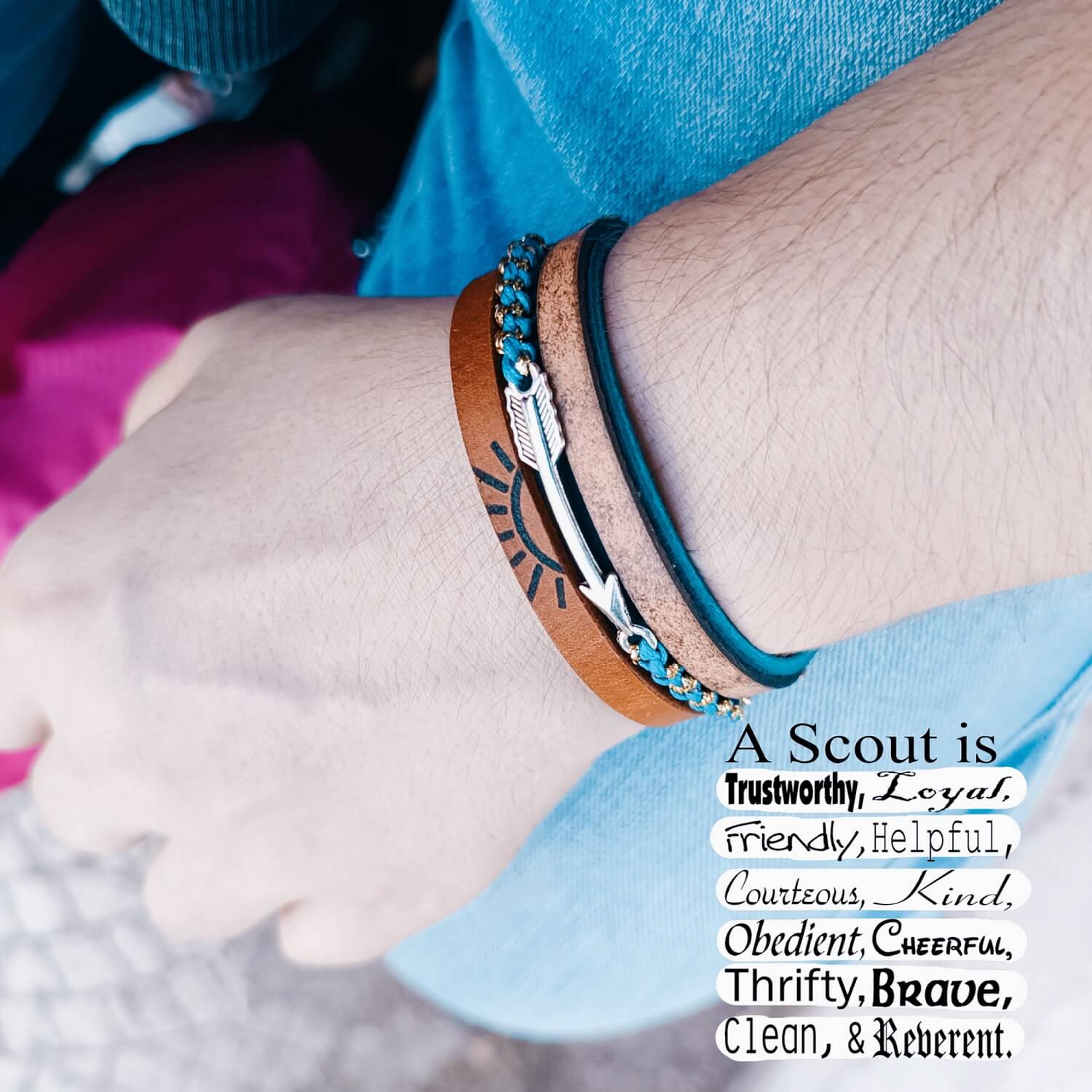 Close-up of a wrist wearing a bracelet with a Scout values quote on a blurred background