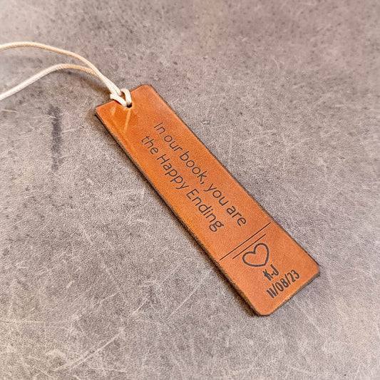 Brown leather bookmark with engraved text on a gray surface